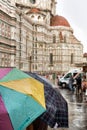 Tourists shelter beneath colorful umbrellas