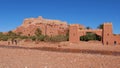 Tourists shooting pictures with a camel below historic Moorish ksar Ait Benhaddou with historic loam buildings.