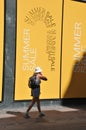 TOURISTS AND SHOPPER WALKS BY SALE SIGN AT ILLUM