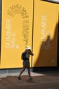 TOURISTS AND SHOPPER WALKS BY SALE SIGN AT ILLUM