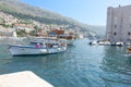 Tourists sightseeing from Old Harbour on tourist boats boat in harbour surrounded by medieval stone walls of Old Town