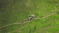 Tourists sitting on green grass by mountain path. Clip. Top view of group of tourists vacationing on green foothills Royalty Free Stock Photo