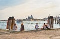 Tourists sitting on the waters edge and enjoying the idyllic scene on Grand Canal in Venice