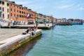 Tourists sitting on the waters edge and enjoying the idyllic scene on Grand Canal in Venice