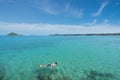 Tourists snorkel in crystal turquoise water near tropical resort Royalty Free Stock Photo