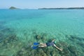 Tourists snorkel in crystal turquoise water near tropical resort Royalty Free Stock Photo