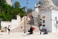 Tourists in the square in the city of Alberobello in front of the romantic staircase.