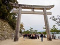 Tourists stand under stone Torii gate, Itsukushima, Hiroshima, Japan
