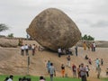 Tourists standing around and siting under Krishna butterball at Mahabalipuram