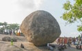 Tourists standing around and siting under Krishna butterball at Mahabalipuram