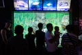 Tourists stop and observe a tank full of fish in an aquarium