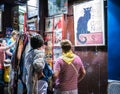 Tourists study souvenirs outside shop under evening lights on Montmartre, Paris