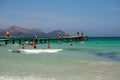 Tourists swim and walk on a long wooden jetty in Playa de Muro, Majorca