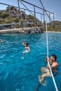 Tourists swimming in sea, holding on to rope walking yacht. Royalty Free Stock Photo