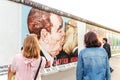 Tourists takes photos with the famous kiss from the Berlin Wall