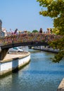 Tourists taking photos and looking at the canal from the arched bridge full of colored strips