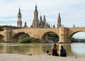 Tourists taking photos to the Basilica of Our Lady of the Pillar and the Stone Bridge in Zaragoza, Spain