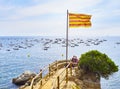 Tourists taking a selfie under Senyera flag in Punta dels Burricaires viewpoint. Calella de Palafrugell, Girona, Catalonia, Spain. Royalty Free Stock Photo