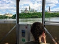 Tourists taking in the views of Parliament Hill and the cityscape while taking a tour boat across the Ottawa River