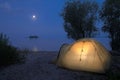 Tourists tents near river. Night moon and island background