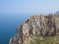 Tourists on the top of the cliff of Olkhon Island. View of Lake Baikal