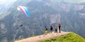 Tourists on top of a mountain pass, taking pictures of a flying paraglider Royalty Free Stock Photo