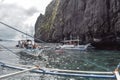 Tourists on traditional Philippino fisherman boats crossing the waters near limestone cliffs of El Nido at Palawan Island the Royalty Free Stock Photo