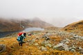 Tourists travelers with backpacks climb the rocks in dense fog. Poor visibility and easy to get lost. Caucasus Mountains Royalty Free Stock Photo