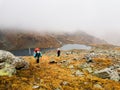 Tourists travelers with backpacks climb the rocks in dense fog. Poor visibility and easy to get lost. Caucasus Mountains Royalty Free Stock Photo