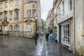 Tourists with umbrellas queuing in the rain outside Sally Lunns Tea House in North Parade Passage, Bath, Somerset, UK