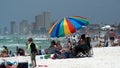 Tourists under a colorful beach umbrella