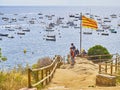 Tourists under a Senyera flag in Punta dels Burricaires viewpoint of Calella de Palafrugell, Catalonia, Spain
