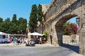 Tourists are visiting souvenir shops near the old arch of Rhodes town fortress.