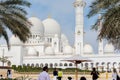 Tourists visiting white Grand Mosque against blue sky, also called Sheikh Zayed Grand Mosque, inspired by Persian, Mughal and