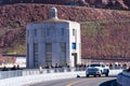 Tourists, visitors and automobile traffic at the top of Hoover Dam. Water intake tower on Arizona side with clock showing Arizona