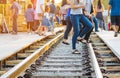 Tourists walk across across rail train tracks from side to another side while visiting The Bridge Over the River Kwai in Royalty Free Stock Photo