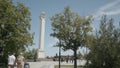 Tourists walk in city park with monument to warrior. Action. Beautiful lively Victory Park with monument and dancing