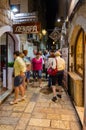 Tourists walk in evening through narrow street of Old Town, Budva, Montenegro