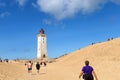 Tourists walk on the sand near the Rubjerg Knude Lighthouse on the coast of the North Sea in the Jutland in northern