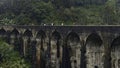 Tourists walk on stone bridge in jungle. Action. People walk on ancient stone bridge in rainforest. Beautiful landscape Royalty Free Stock Photo