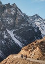 Tourists walk to black mountain with snow on the top and yellow stone ground at Thangu and Chopta valley in winter in Lachen. Royalty Free Stock Photo