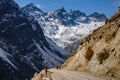 Tourists walk to black mountain with snow on the top and yellow stone ground at Thangu and Chopta valley in winter in Lachen. Royalty Free Stock Photo