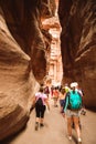 Tourists walk towards treasury landmark in Petra through The Siq, the narrow slot-canyon that serves as the entrance passage to