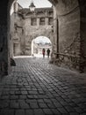 Tourists walking on the cobblestone street between the walls of Sighisoara fortress in Romania Royalty Free Stock Photo