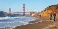 Tourists walking with dog on Baker beach, Golden gate bridge, San Francisco, USA Royalty Free Stock Photo