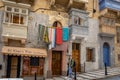 Tourists walking down the street in Valletta, Malta. Traditional maltese balconies and colourful hanging laundry.