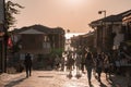 Tourists walking on footpath amidst old shops leading towards sea at sunset