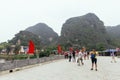 Tourists walking on the ground near Trang An Landscape Complex with mountain in the background in summer in Ninh Binh, Vietnam