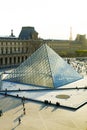 Tourists walking in Louvre near amazing glass pyramid, Paris, France.