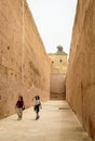 Tourists walking near the high ancient walls inside Marrakech Badi Palace